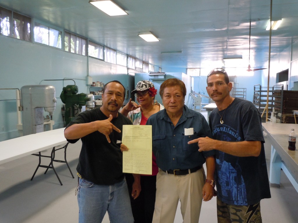Bakery owner George Kanemitsu, second from right, holds the reinstated permit, accompanied by community members and volunteer contractors. Photo by Catherine Cluett