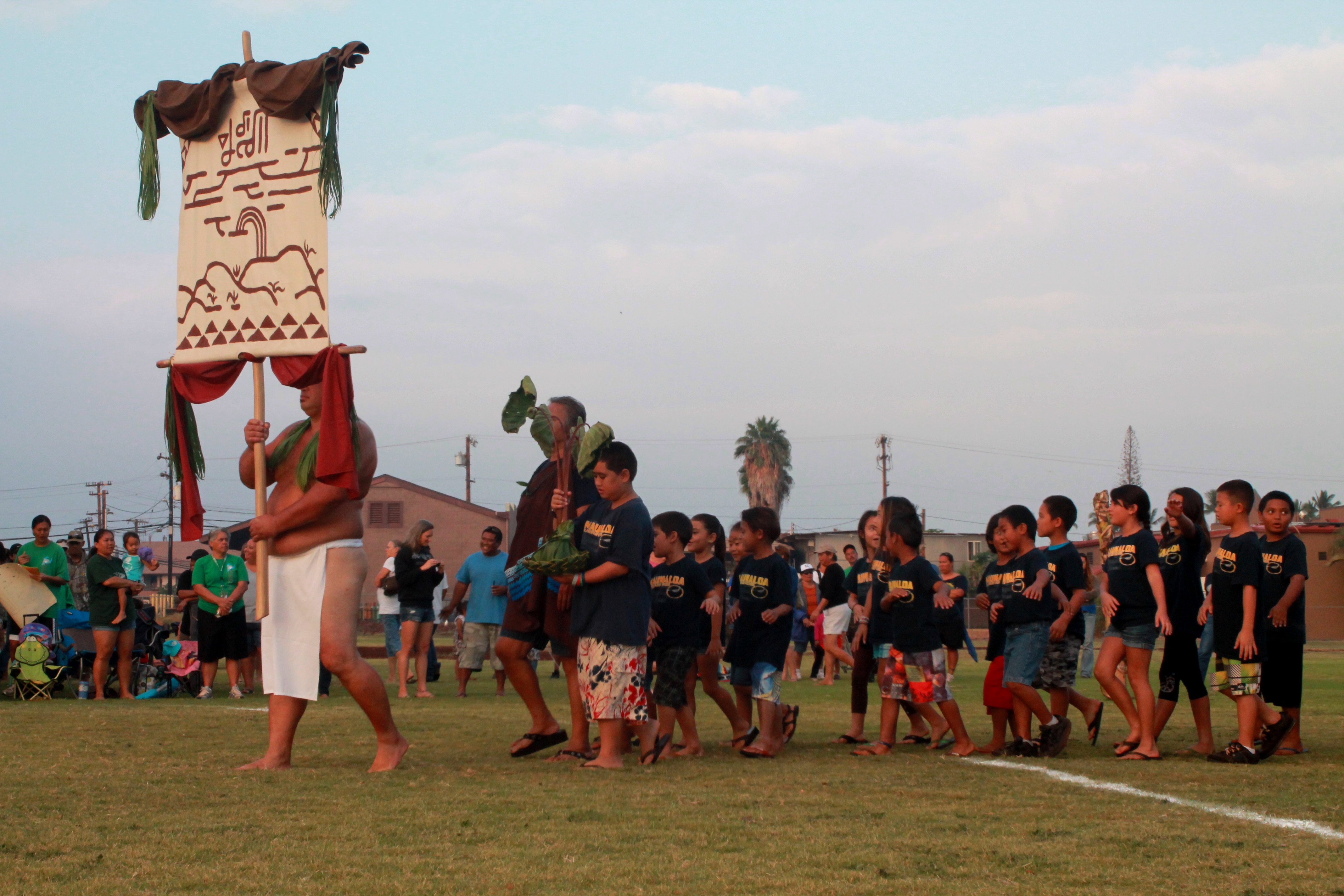 Makahiki competitors enter the game arena with their ho`okupu to Lono.
